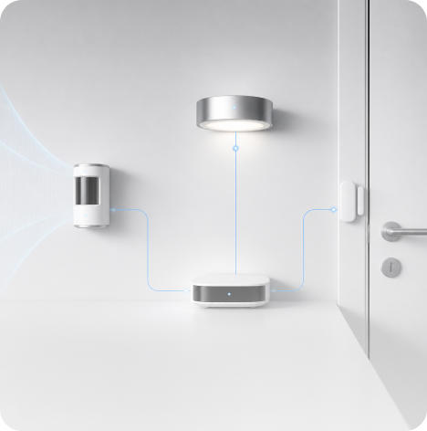 Smart home devices including motion sensor, light, and door sensor connected wirelessly on a white wall and desk.